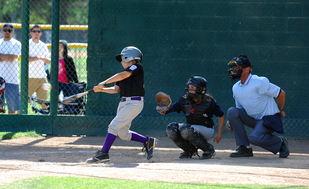 Youth baseball game, the batter is hitting the ball with the catcher and umpire behind him.